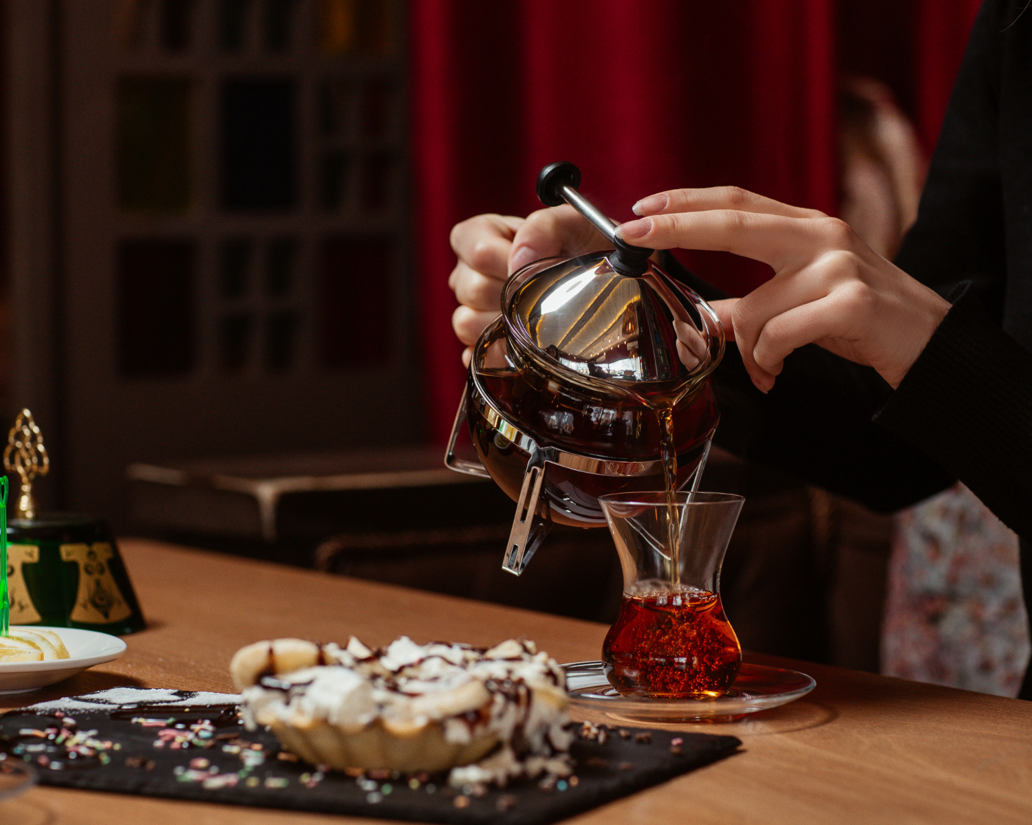 woman putting glass tea tea table with sweets